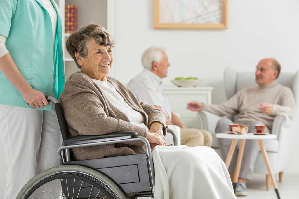 Residents share a balanced meal at a bright assisted living dining table with vegetables, soup, and water.